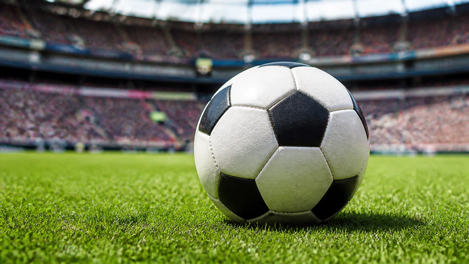 Ein Fußball auf dem Rasen vor einer spanischen Fankulisse