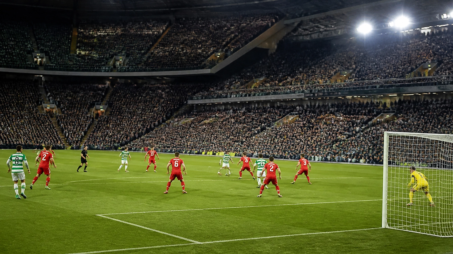 Spielszene mit einer offensiven Heimmannschaft in Grün-Weiß und einer kompakten Auswärtsmannschaft in Rot-Weiß