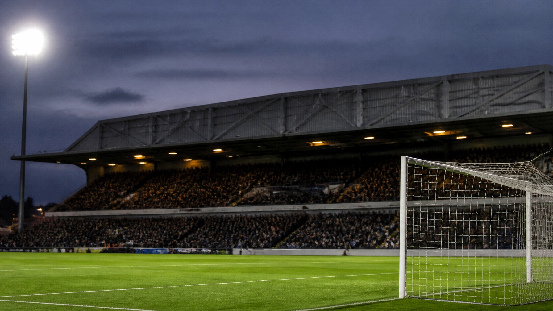 Englische Fußballstadionatmosphäre am Spieltag mit Tor und Flutlicht